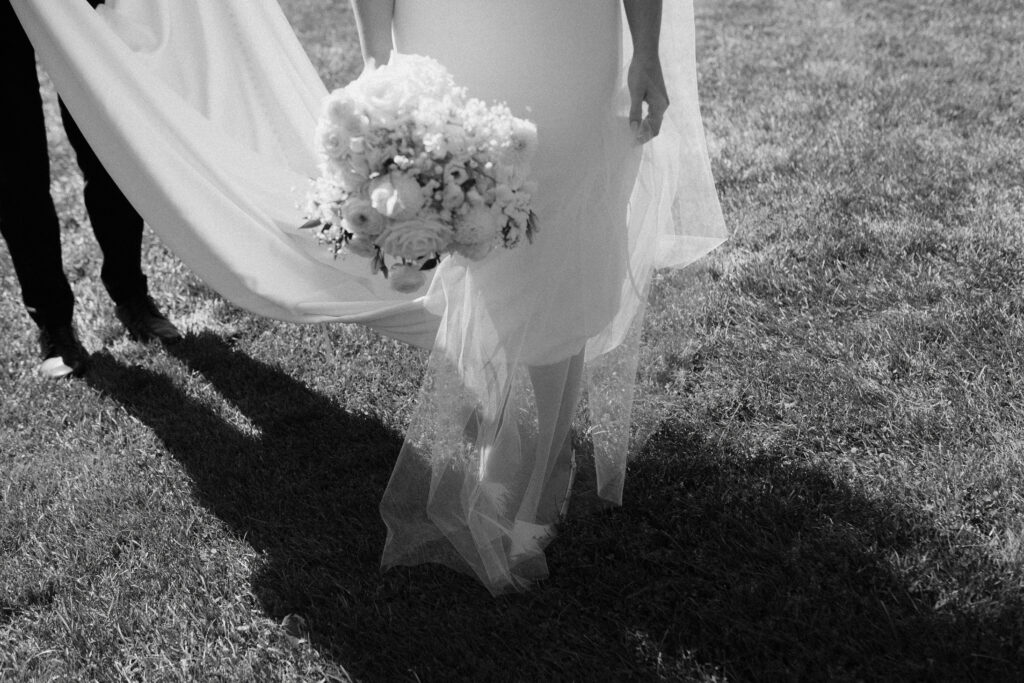 Black and white image of bride holding her bouquet, covered by her veil