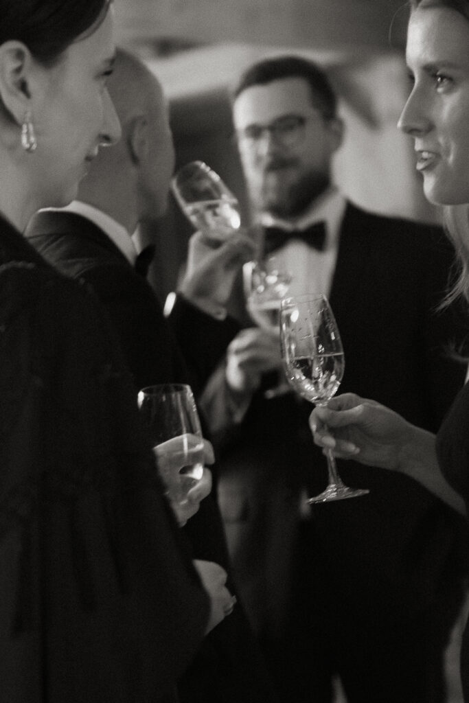 Candid black and white photos of guests sipping champagne at a wedding