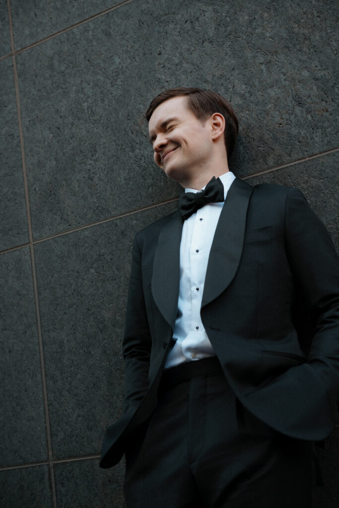 Editorial portrait of groom standing alone in the Distillery District, framed by moody light and historic brick architecture.