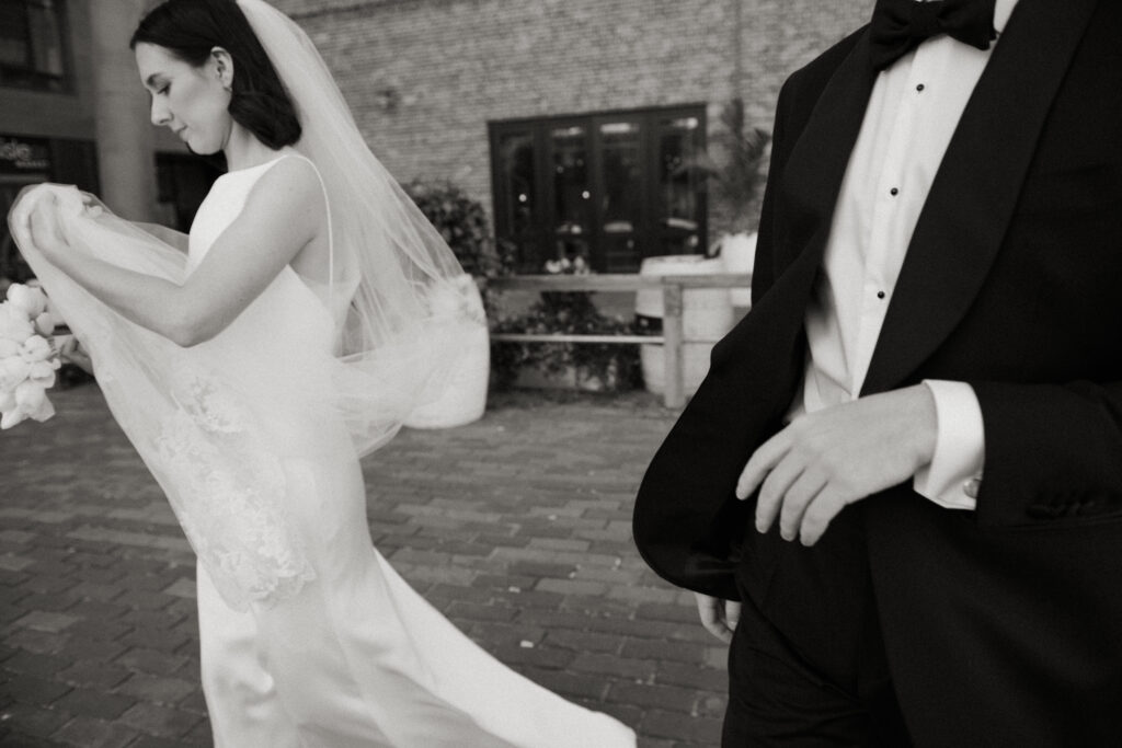 Black and white wedding photo of couple walking through cobblestone streets of Toronto’s Distillery District.